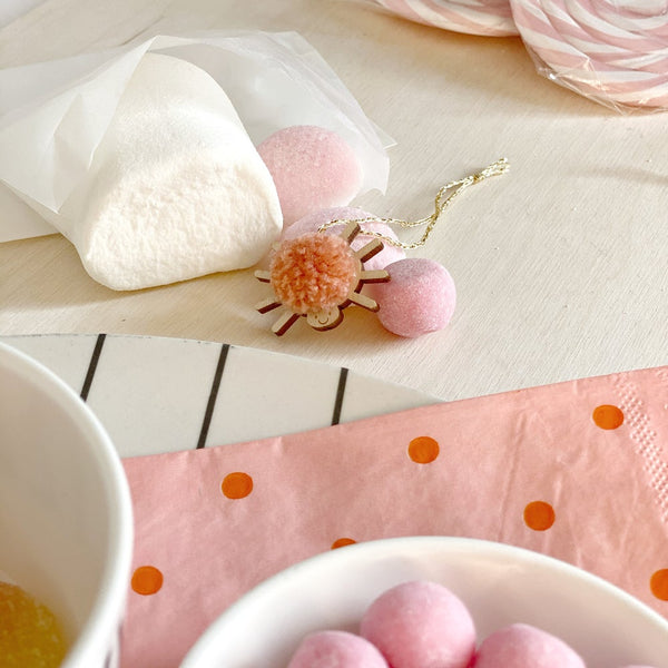 Mini pompom spider close up next to marshmallows