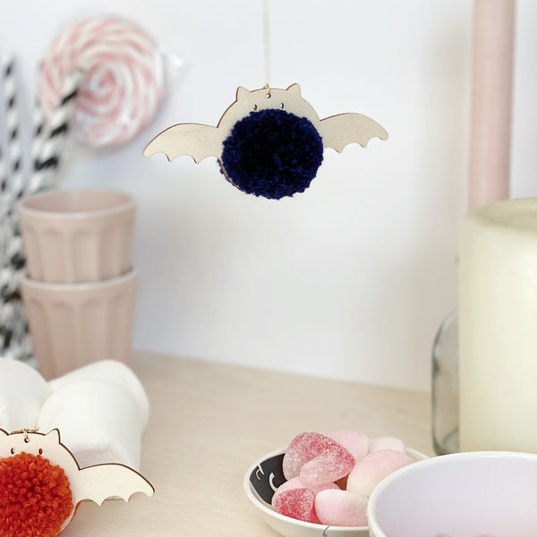 pompom black bat hanging with red pompom bat on table