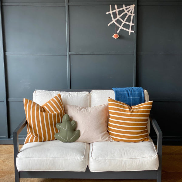 Web and pompom smiley spider against a wall with sofa below