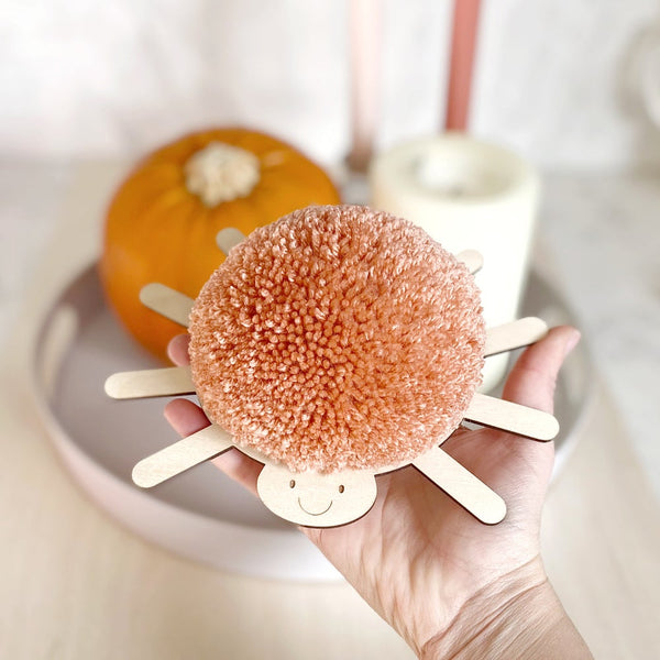 big pompom spider with peach pompom in hand