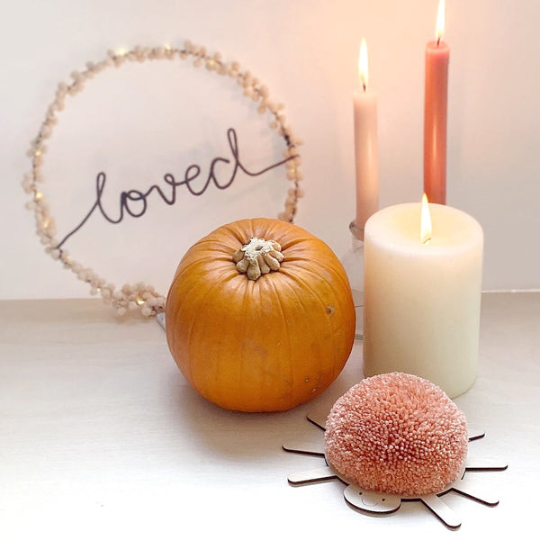 halloween decor set up with pom pom spider, candle, wire wording and pumpkin