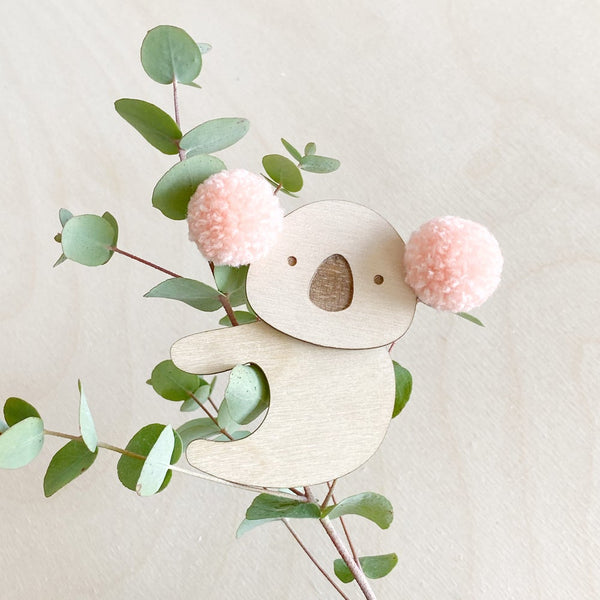 Pink pompom koala clipped onto house plant