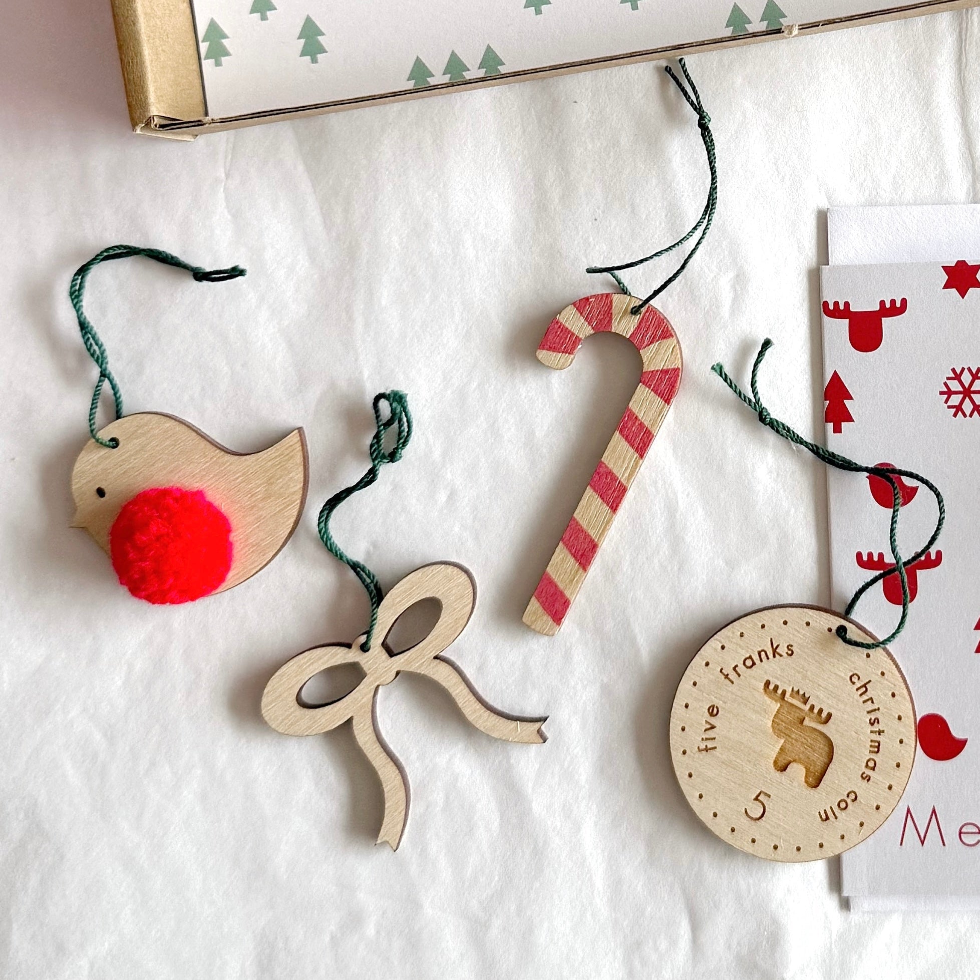 Wooden Christmas ornaments and a card on a white surface with a patterned background