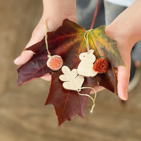 Harvest mini decorations laid on autumn leaf with pom poms
